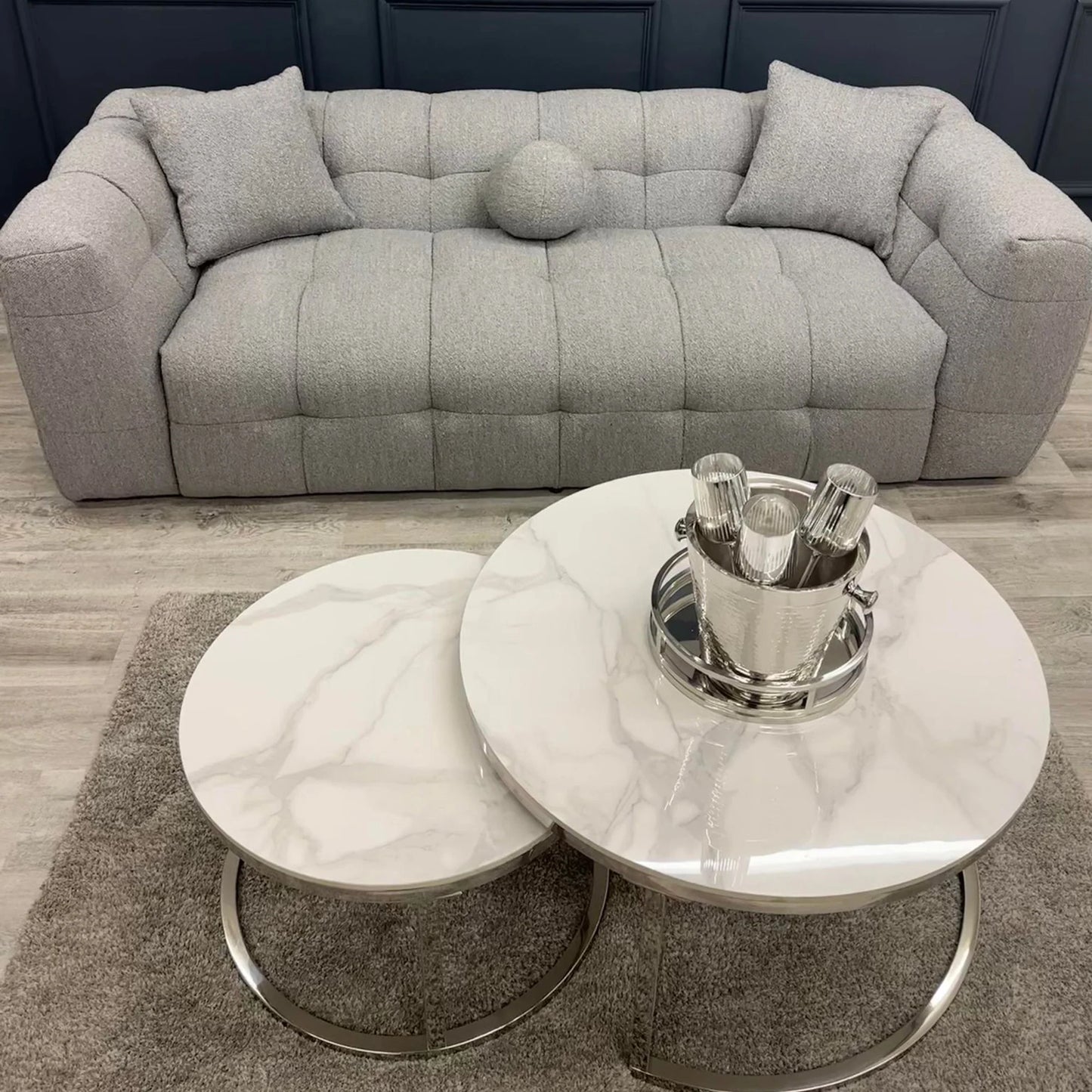 Grey bouclé 3 seater sofa with deep tufting and soft curved design, styled in a contemporary living room with round marble coffee tables and minimalist decor.