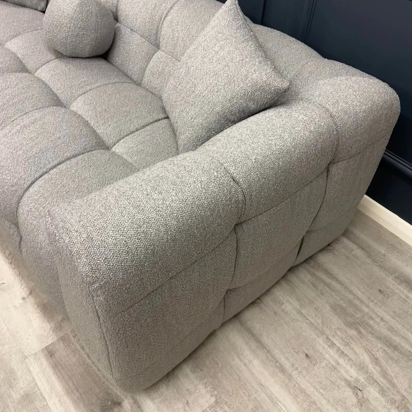 Grey bouclé 3 seater sofa with deep tufting and soft curved design, styled in a contemporary living room with round marble coffee tables and minimalist decor.