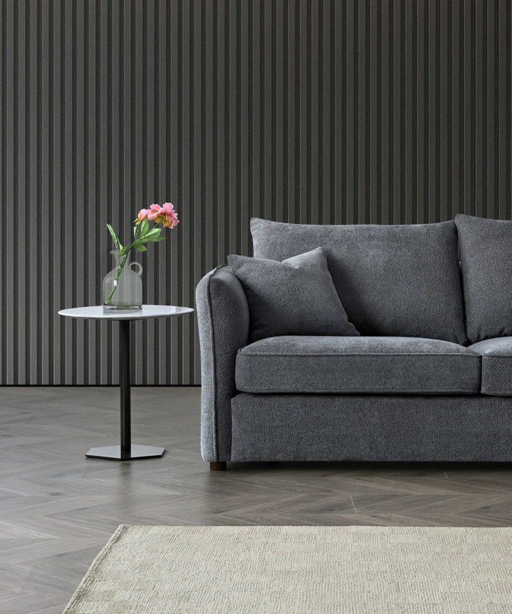 Rubin curved corner chaise sofa upholstered in charcoal bouclé fabric, featuring a sculptural design with deep cushions and a modern organic silhouette, styled in a luxury living room setting