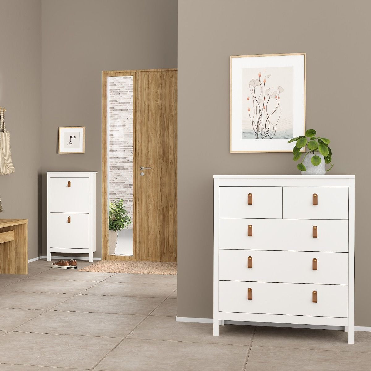 White dresser with brown handles in a room with a mirror, desk, and wall art.