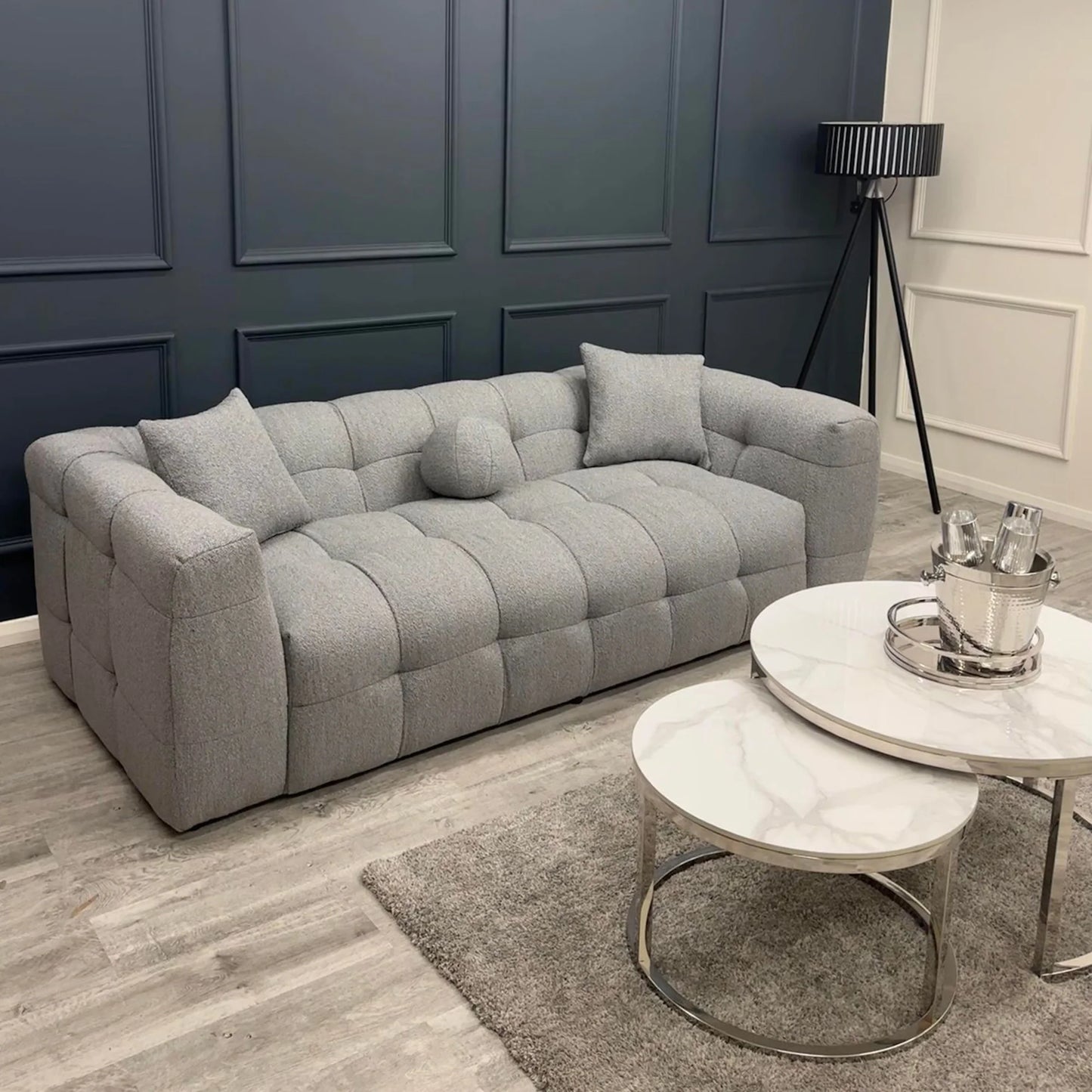 Grey bouclé 3 seater sofa with deep tufting and soft curved design, styled in a contemporary living room with round marble coffee tables and minimalist decor.
