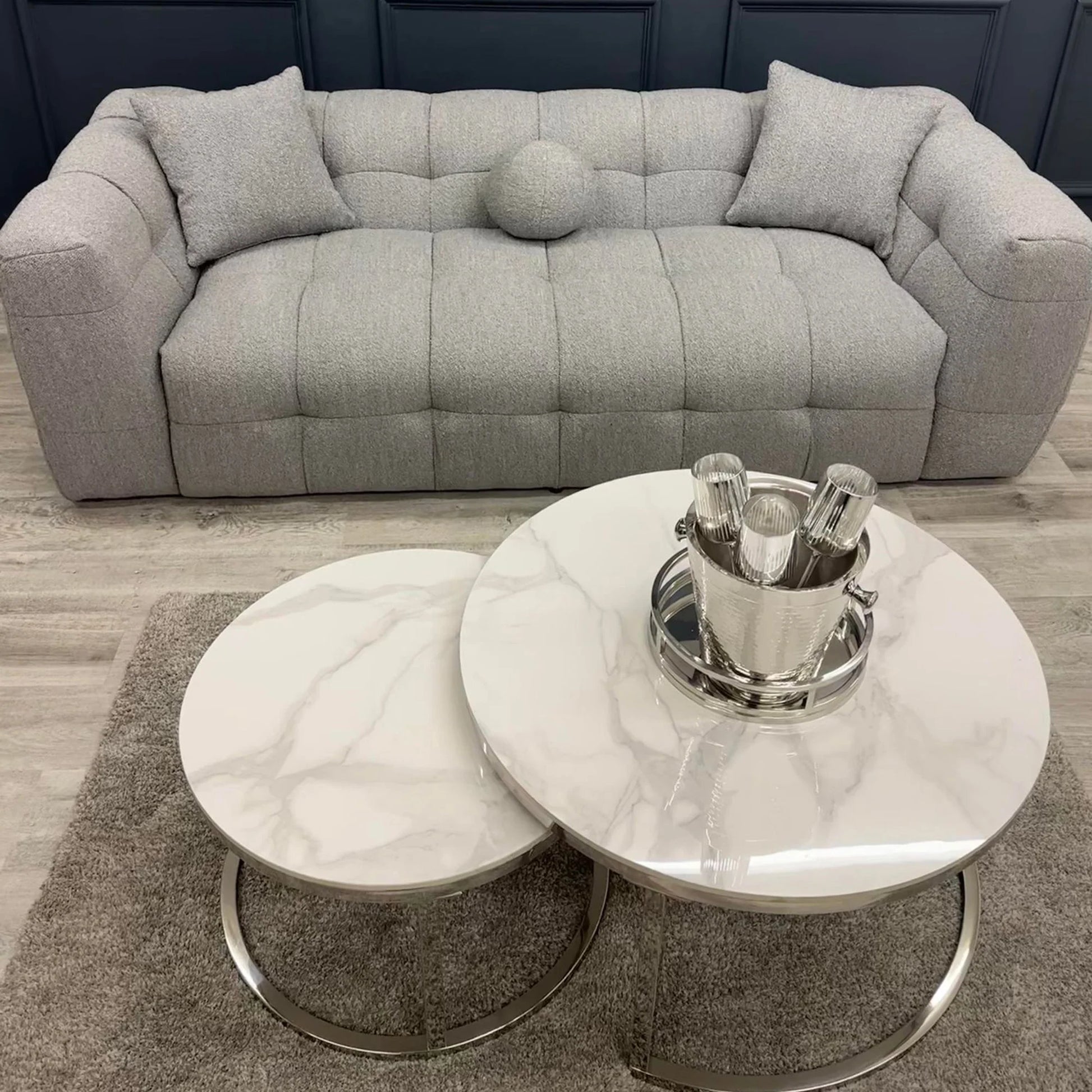 Grey bouclé 3 seater sofa with deep tufting and soft curved design, styled in a contemporary living room with round marble coffee tables and minimalist decor.