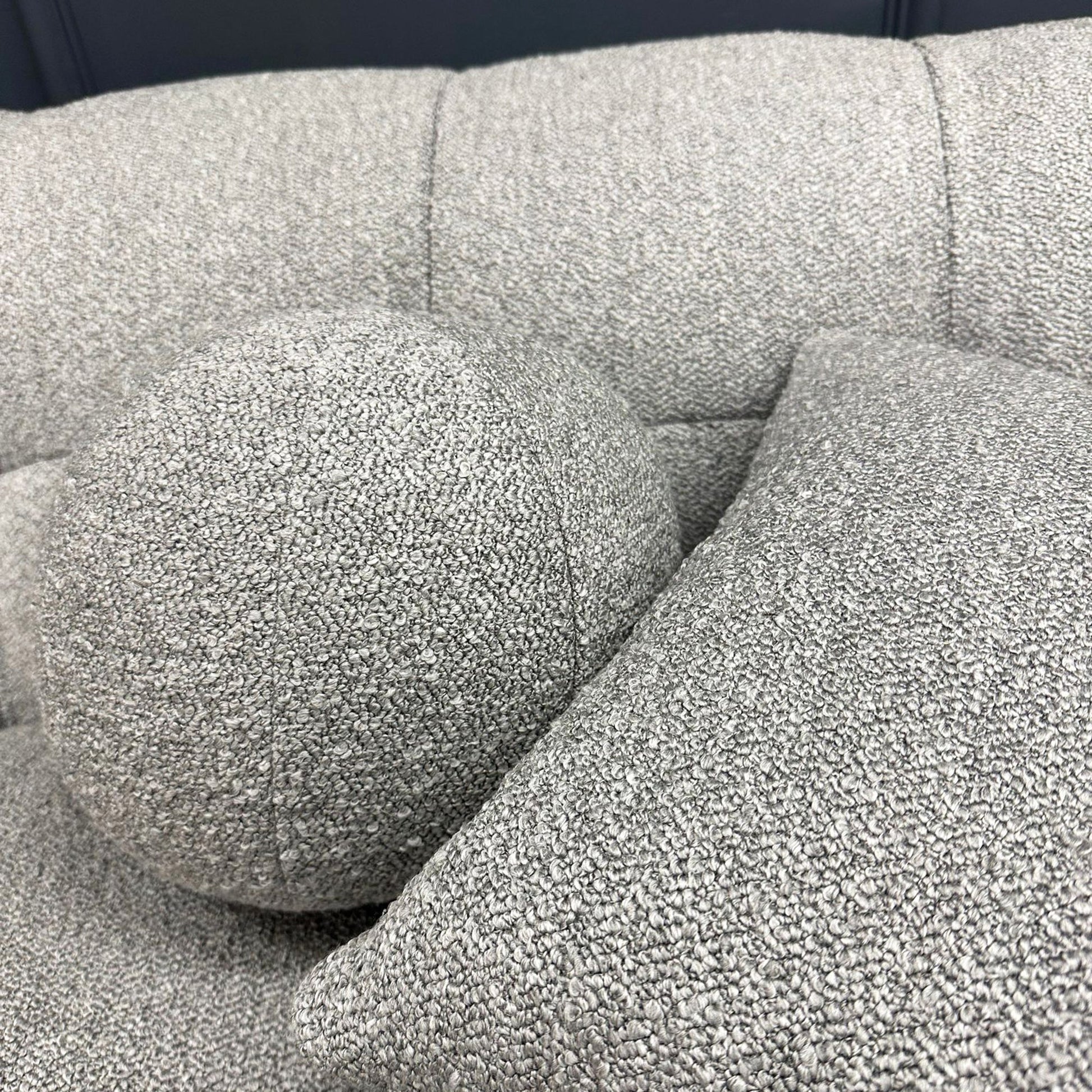 Grey bouclé 3 seater sofa with deep tufting and soft curved design, styled in a contemporary living room with round marble coffee tables and minimalist decor.