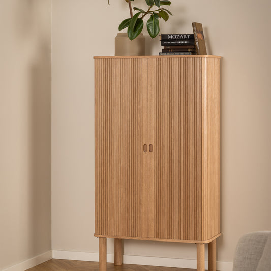 Tall oak cabinet with slatted vertical tambour doors, rounded corners, and adjustable shelving, designed in a Scandinavian minimalist style.