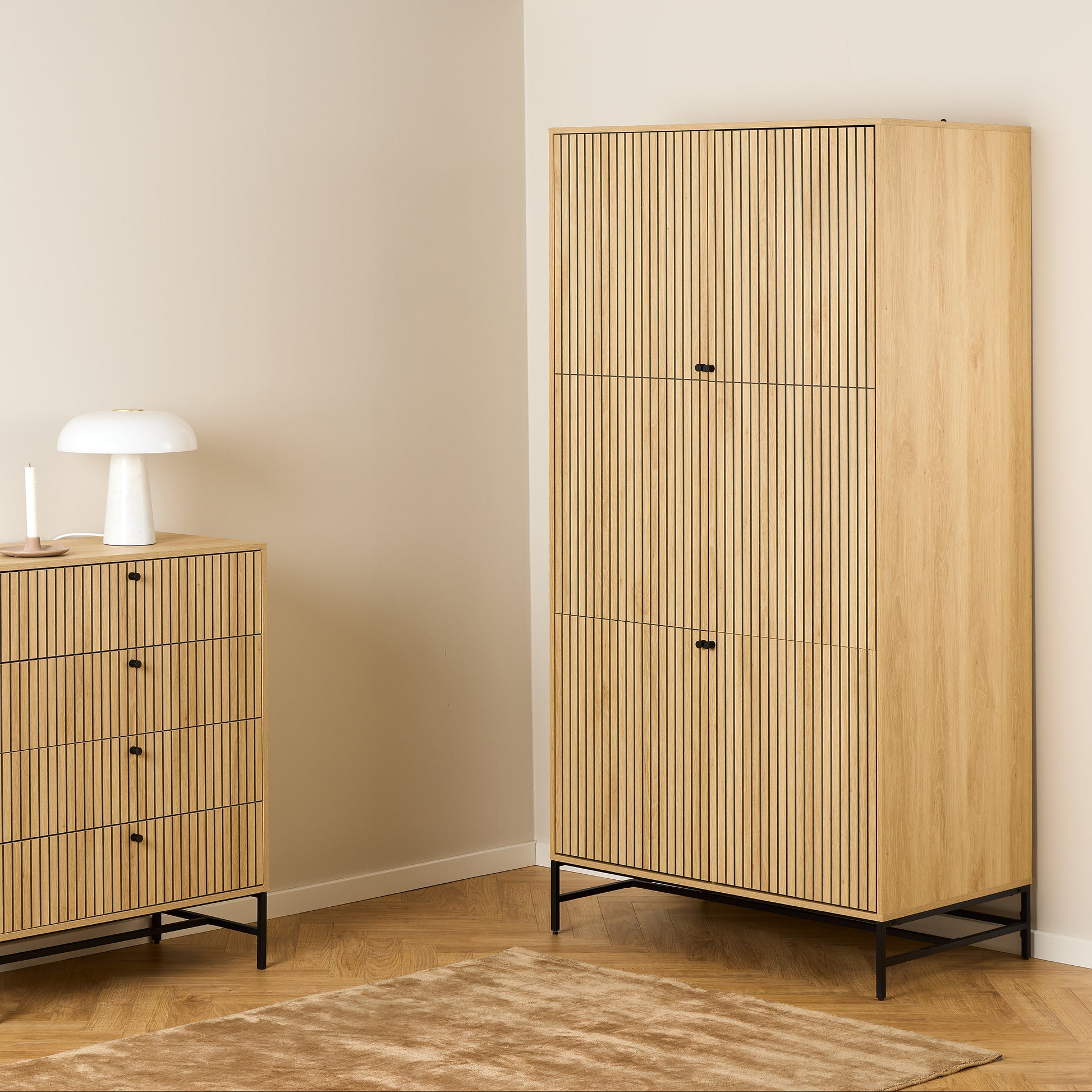 Large oak wardrobe with 4 vertically slatted doors and black steel base, opened to reveal hanging space and shelves, styled in a modern Scandinavian bedroom.