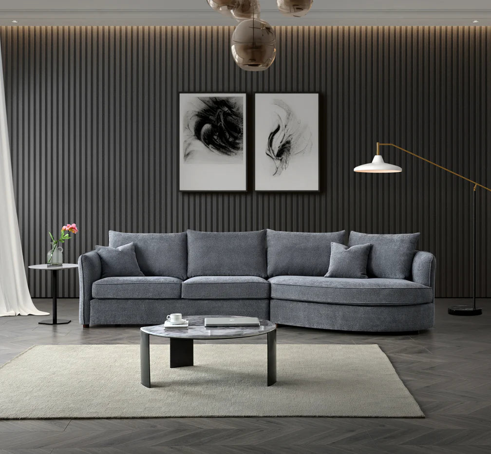 Rubin curved corner chaise sofa upholstered in charcoal bouclé fabric, featuring a sculptural design with deep cushions and a modern organic silhouette, styled in a luxury living room setting