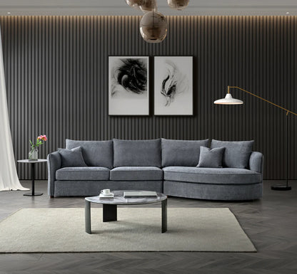 Rubin curved corner chaise sofa upholstered in charcoal bouclé fabric, featuring a sculptural design with deep cushions and a modern organic silhouette, styled in a luxury living room setting