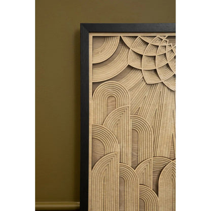 Wooden wall art with geometric pattern in a black frame against a green wall.